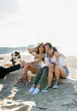 Happy Female Friends With Dog Taking A Selfie On The Beach