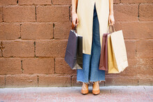 Woman Carrying Shopping Bag While Standing Against Brick Wall