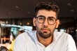 © Thomas Degen/Westend61 - Portrait of pensive young businessman with beard and glasses at sidewalk cafe