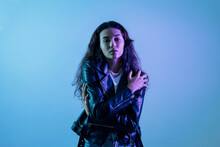 Confident Teenage Girl Wearing Leather Jacket Posing Against Blue Background