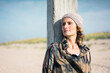 © Robijn Page/Westend61 - Woman with woolly hat leaning on wood pole
