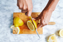 Hands Of Woman Cutting Lemons On Cutting Board