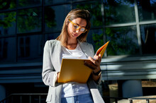 Businesswoman Taking With Note Book Outside Office Building