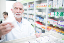Pharmacist Taking Medicine From Cabinet In Pharmacy
