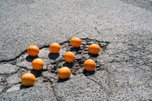 Group Of Oranges Lying In Asphalt Cracks #