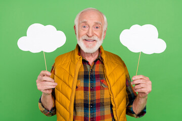 Photo of charming cute mature man dressed yellow waistcoat holding two speaking bubbles empty space isolated green color background