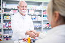 Pharmacist And Customer Shaking Hands In Pharmacy