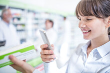 Smiling Woman In Pharmacy Holding Smartphone And Medicine