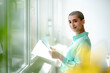 © KNSY/Westend61 - Portrait of smiling businesswoman holding papers at the window in loft office