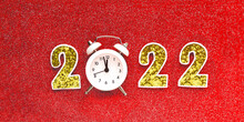 2022 With Gold Numbers And White Alarm Clocks On A Bright Red Glitter Background..