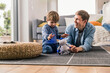 © UWE_UMSTAETTER/Westend61 - Father and son lying on floor, playing with toy robot