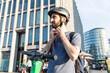 © William Perugini/Westend61 - Man using e-scooter in Berlin, fastening safety helmet, Germany