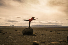 Young Woman Balancing On One Leg On A Rock In The Volcanic Highlands Of Iceland