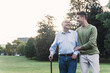 © UWE_UMSTAETTER/Westend61 - Young man assisting his grandfather walking in a park
