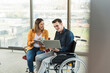 © UWE_UMSTAETTER/Westend61 - Happy young businessman with laptop in wheelchair and businesswoman with tablet in office