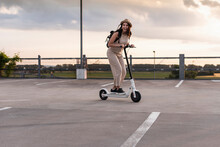 Happy Young Woman On Electric Scooter On Parking Deck