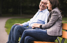 Senior Man And Granddaughter Relaxing Together On A Park Bench
