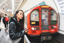 Portrait Of Woman With Smartphone Waiting At Underground Station Platform, London, UK