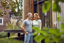 Cheerful Couple Looking At Each Other While Standing In Front Of Tiny House