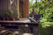 © Maya Claussen/Westend61 - Mature man using laptop while sitting against tiny house