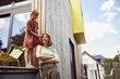 © Maya Claussen/Westend61 - Girl tying mother's hair while standing outside tiny house