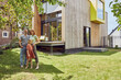 © Maya Claussen/Westend61 - Family standing outside tiny house in yard