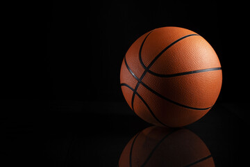 Sticker - Closeup shot of a brown basketball ball with black stripes on a black background with a reflection