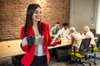 © Dragana Gordic - Shot of young business woman entrepreneur looking at camera in the office. In the background, her colleagues working. Beautiful business woman Texting in the coffee break