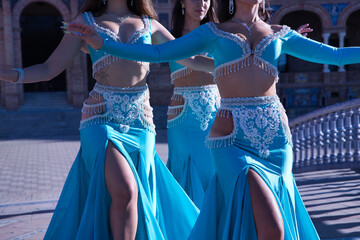 Wall Mural - Detail of waists of three middle-aged Hispanic women, wearing turquoise costumes and rhinestones, to dance belly dance. Belly dance concept.