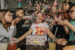 © Mareen Fischinger/Westend61 - Happy friends throwing confetti on teenage girl sitting with birthday gift at dining table