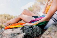 Young Woman With Rainbow Flag Sitting On Rock