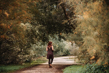 Young Woman Walking On Footpath Amidst Plants In Forest