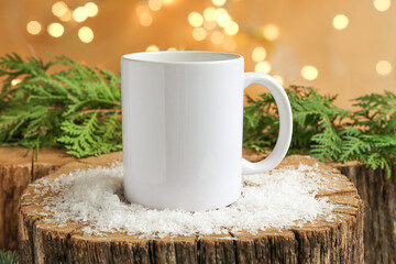 White coffee mug on a wooden Christmas background with snow, green branches and beautiful bokeh. Copy space, mockup for advertising.