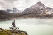 © Manuel Sulzer/Westend61 - Mountain biker looking at view of Griessee lake while standing at Nufenenpass, Valais, Switzerland