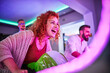 © Dangubic/Westend61 - Woman playing and having fun with a driving simulator in an amusement arcade