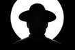 © Manuel Sulzer/Westend61 - In silhouette of man wearing hat standing against illuminated lighting equipment