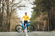 © Mikel Taboada Blanco/Westend61 - Smiling young man in sports clothing standing with mountain bicycle on country road