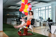 © peter scholl/Westend61 - Businesswoman holding balloon while sitting on rocking horse at office
