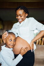 Little Boy Listening At Belly Of Pregnant Young Woman