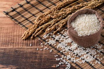 Wall Mural - Raw white rice in a wooden bowl over table.