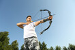 Man with bow and arrow practicing archery outdoors, low angle view