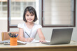 Asian children girl student writing on notebook while studying online via laptop while at home. Education Concept Stock Photo