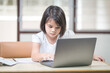 © EduLife Photos - Asian children girl student writing on notebook while studying online via laptop while at home. Education Concept Stock Photo