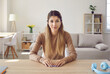 © Studio Romantic - Portrait of cute friendly young woman who is looking at webcam while sitting at home in living room. Modern girl blogger recording video for blog or making video call at home. Lifestyle concept.