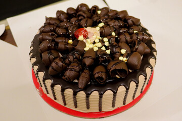 Sticker - Closeup shot of a vanilla cake covered with chocolate candies and glazing on a white surface