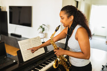 Ethnic Musician Pointing At Sheet Music While Playing Saxophone