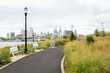 Walking path through the plants and grasses growing at RCA Pier Park on the Camden Waterfront, New Jersey, USA, with the Philadelphia skyline in the distance