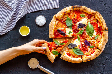 Female hands hold slice of pizza. Overhead view