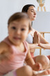 © Вадим Каштанов - Woman and little girl meditate in lotus position. Yoga class. Natural emotions and fun. Blurred foreground.