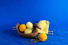Balls Of Acrylic Yarn, Knitting Needles, Knitting And A Basket In The Shape Of A Duck